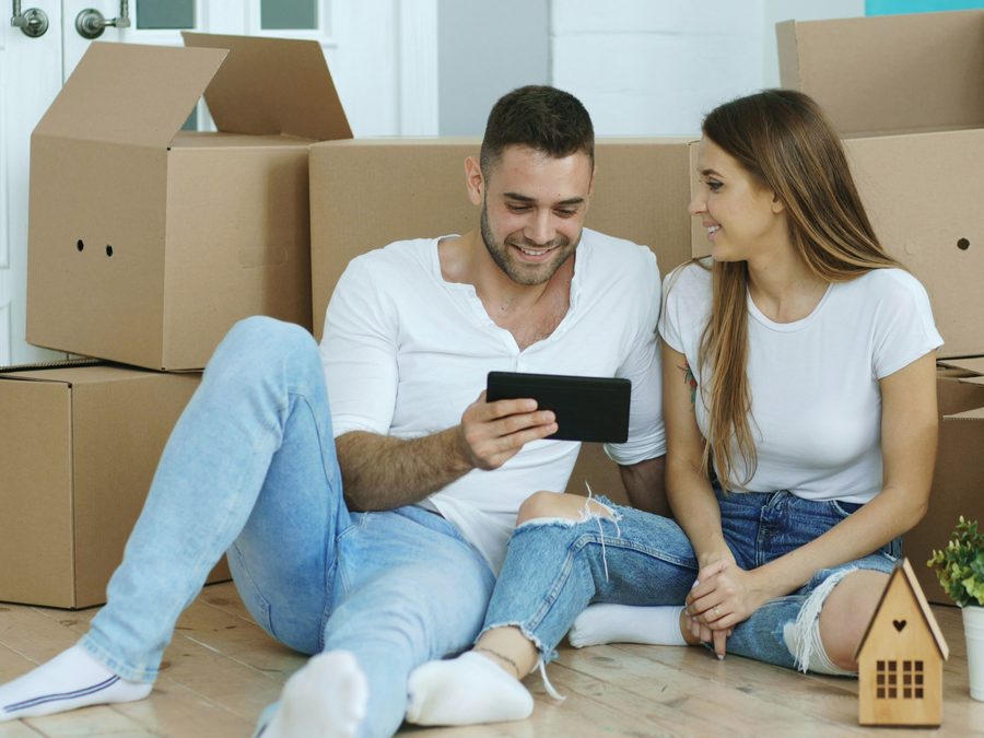 A young couple sitting among moving boxes in their new home